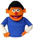 Skip is an orange puppet puppet with black hair.